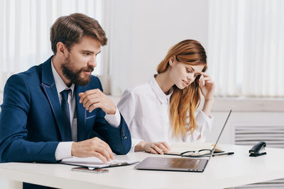 Business people using laptop while sitting at office