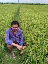 Portrait of farmer crouching on field