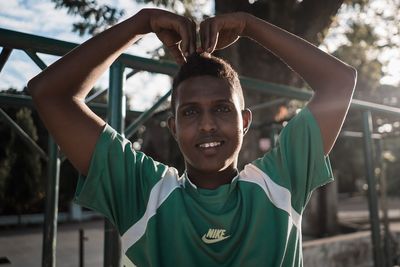 Portrait of smiling man touching head outdoors