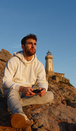 Portrait of boy sitting with a lighthouse with mobile phone person