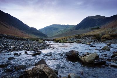 Scenic view of stream in mountains against sky