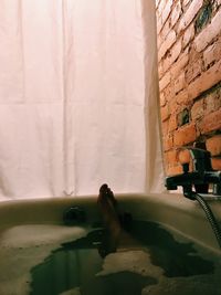 Low section of person relaxing in bathtub at bathroom