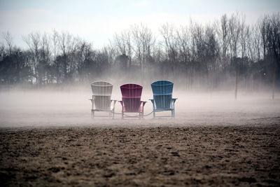 Empty chair on field against sky