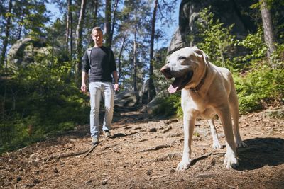 Woman with dog standing in forest