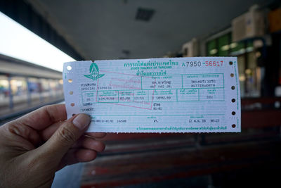 Cropped hand holding ticket at railroad station platform