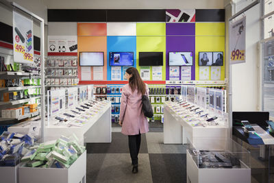 Rear view of female customer viewing smart phones in store