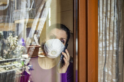 Portrait of woman holding glass window