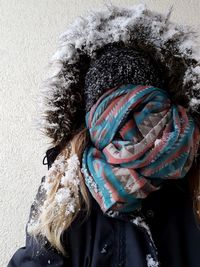 Woman with obscured face standing against wall during winter