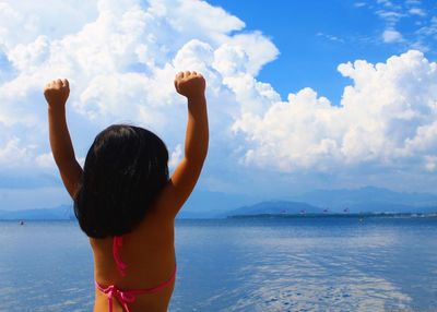 Rear view of young girl against sea against sky