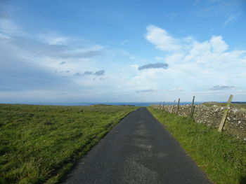 Road amidst green landscape against sky