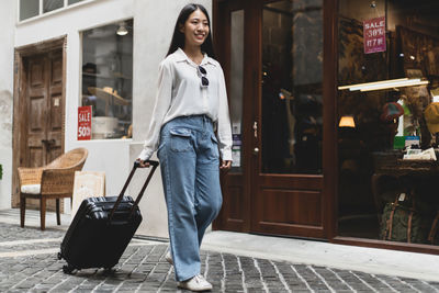 Full length portrait of smiling woman standing outdoors