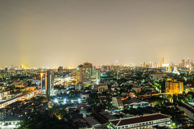 High angle view of illuminated city buildings against clear sky