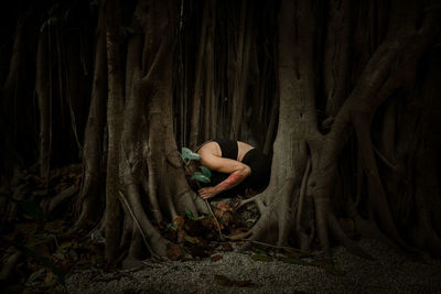 Woman standing by tree trunk