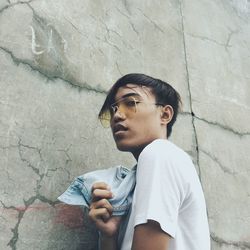 Low angle portrait of teenage boy standing by wall