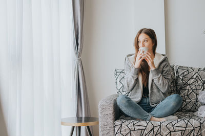 Portrait of woman sitting by window at home