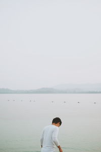 Rear view of man standing next to sea