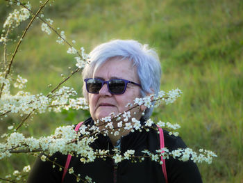 Senior woman looking away by flowers blooming in park