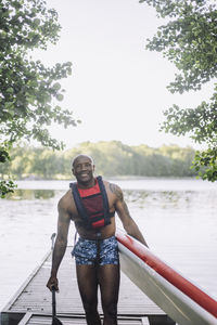 Smiling man with paddleboard standing on jetty