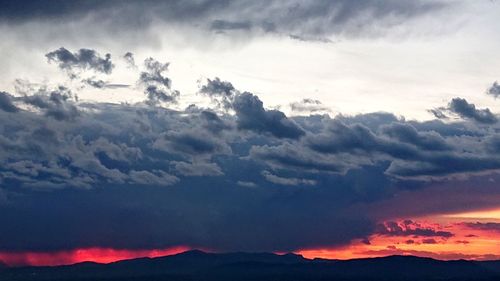 Scenic view of dramatic sky over silhouette mountains during sunset