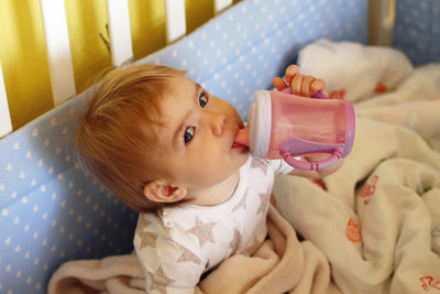 Portrait of cute baby lying on bed at home