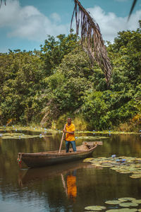 Scenic view of a man standing in a boat in a river