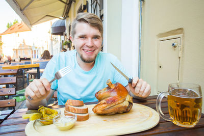 Portrait of a smiling young man having food in restaurant