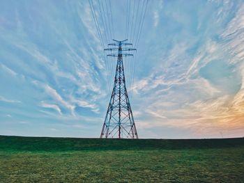 Low angle view of electricity pylon on field against sky