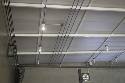 Low angle view of illuminated lights on ceiling of building