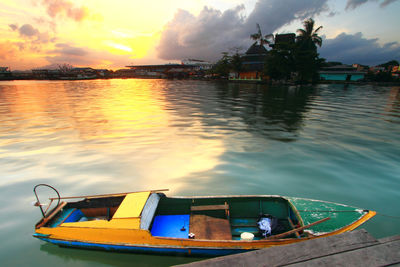 Boat moored on sea against sky during sunset