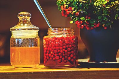 Red berries and honey in jars on table
