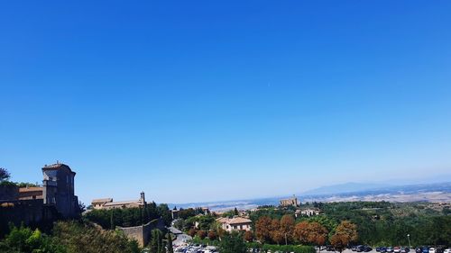 Buildings in city against clear blue sky