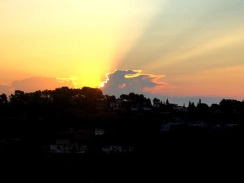 Silhouette trees and cityscape against sky during sunset