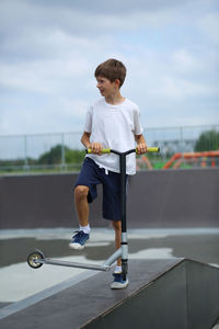 Active ten year old boy riding a scooter in the summer skate park