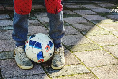 Low section of man with ball on footpath