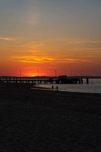 Silhouette pier on beach against sky during sunset