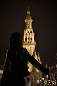 Midsection of woman at illuminated temple against sky at night