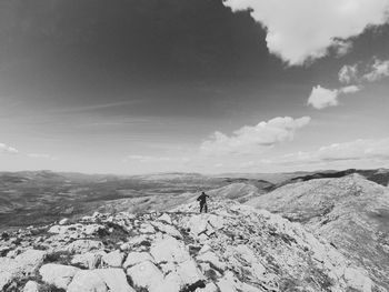 Man standing on rock against sky