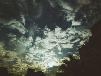 Low angle view of silhouette trees and building against sky