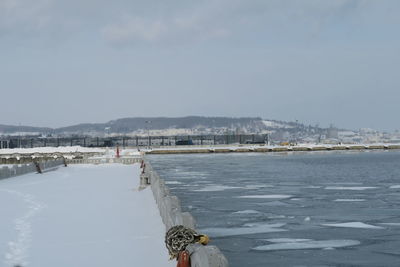 Scenic view of sea by city against sky during winter