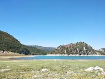 Scenic view of sea and mountains against clear blue sky