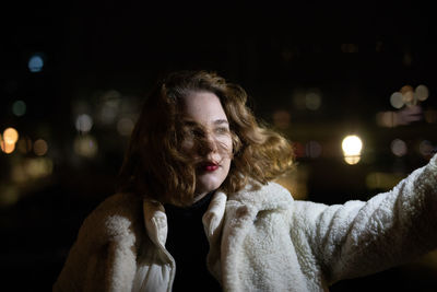 Young woman standing in city during winter at night