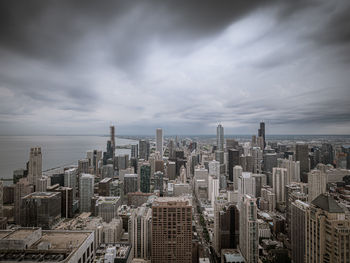 Aerial view of buildings in city against cloudy sky