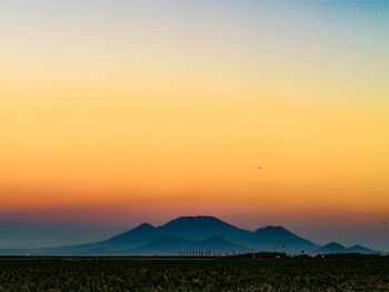 Scenic view of silhouette field against romantic sky at sunset