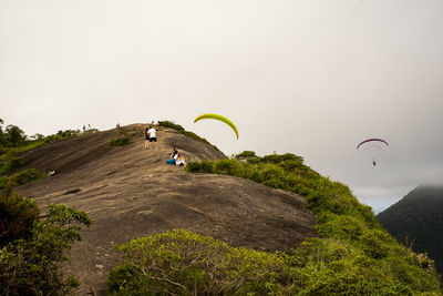 People flying over mountain against sky