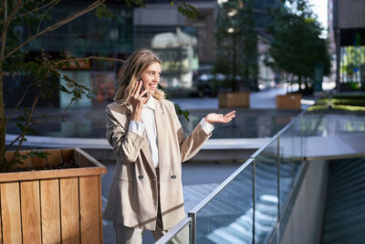 Side view of young woman looking away while standing in city