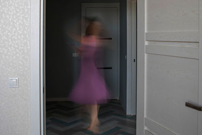 Blurred motion of woman standing by window at home