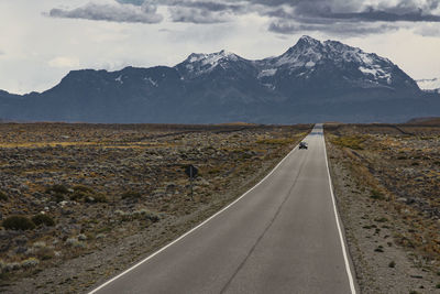 Road by snowcapped mountains against sky