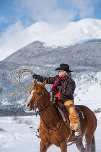 Man riding horse on snow covered landscape