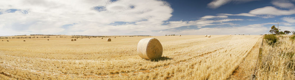 Hay bales on field against sky