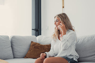 Young woman using mobile phone while sitting on sofa at home